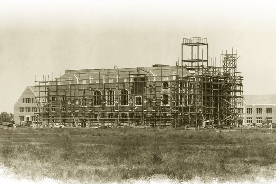 A sepia-toned archival photo of a campus building under construction.