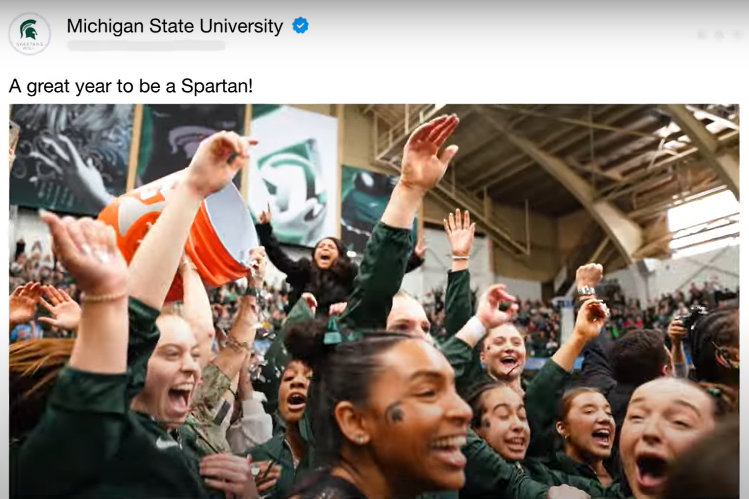 Screenshot from MSU's year in review video shows a screenshot of the Facebook post with the caption "A great year to be a Spartan!" The image is of its girls gymnastics team celebrating their championship win.