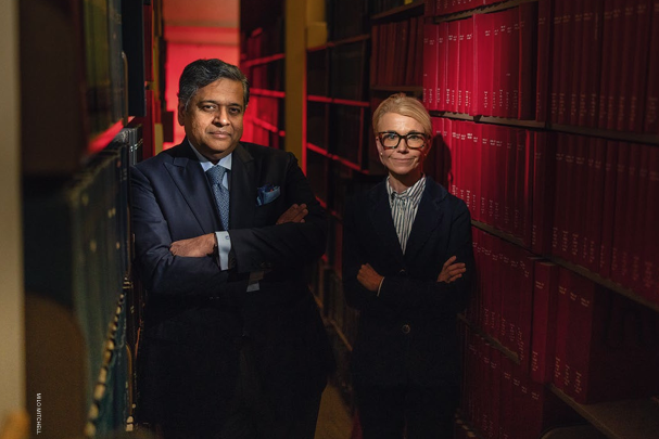 Dr. Kalyanam Shivkumar (left) and Dr. Barbara Natterson-Horowitz (right) each with their arms crossed pose of camera between two rows of bookselves.