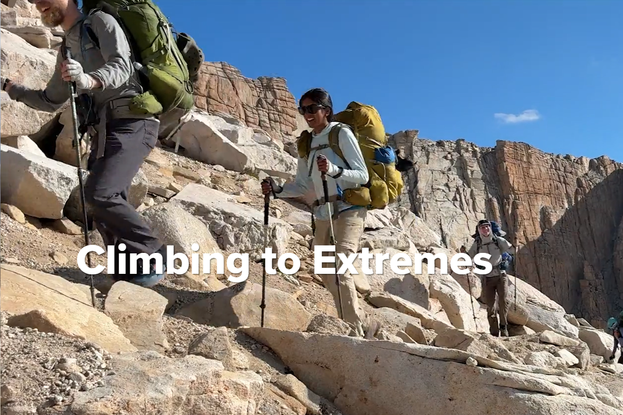 Four hikers climb across a rock formation behind the headline "Climbing to Extremes."