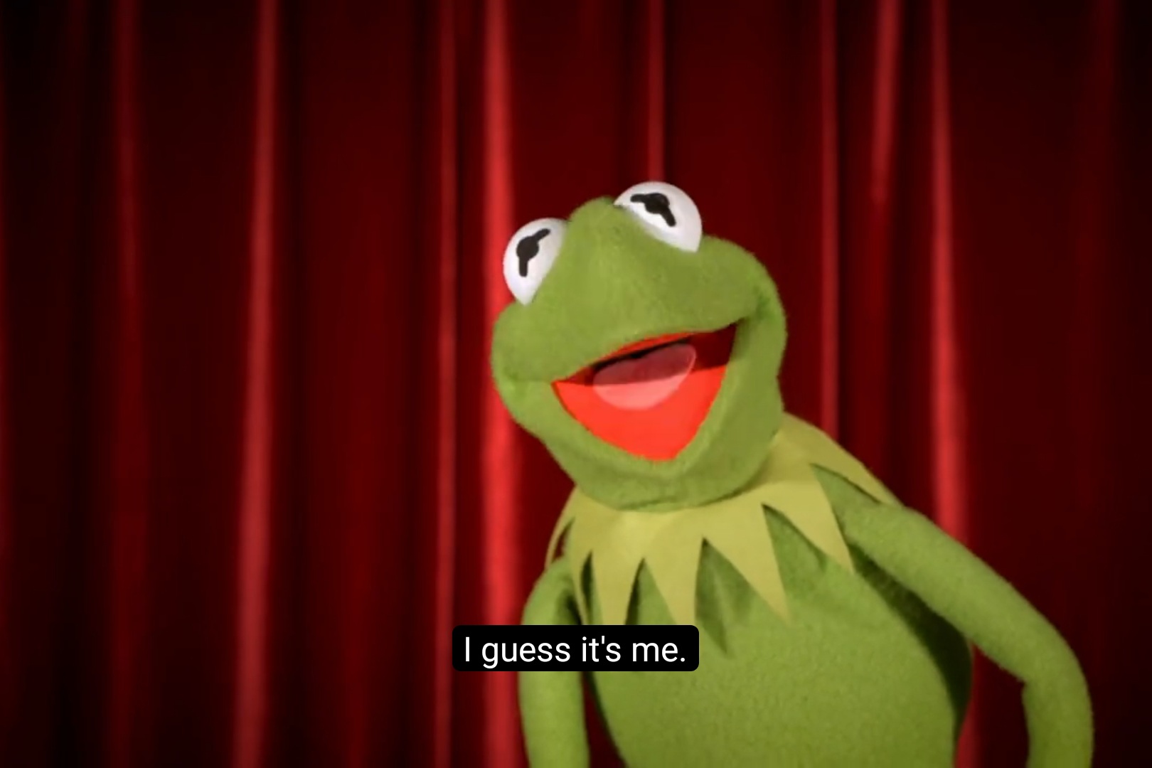 Kermit the Frog says, "I guess it's me" in front of a red curtain.
