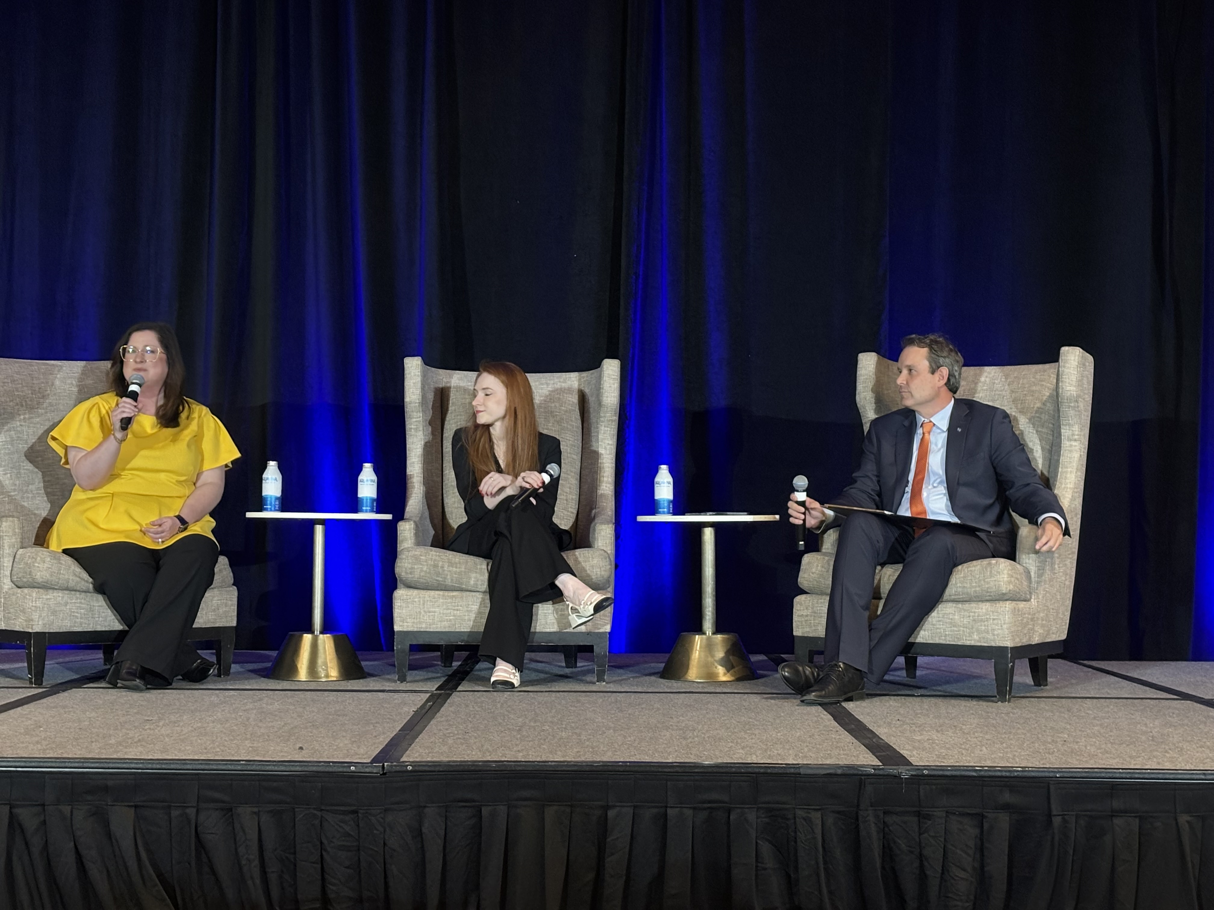 Dr. Jennifer Lawrence, Kathryn Gimborys, and Brian Flahaven siting on stage during opening plenary