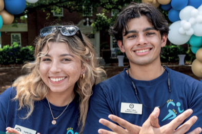Two UNCW students smile for camera wearing matching UNCW-branded T-shirts.
