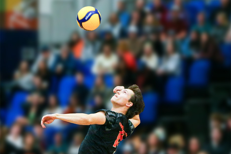 Owyn McInnis jumps in the air, preparing to hit a yellow volleyball.