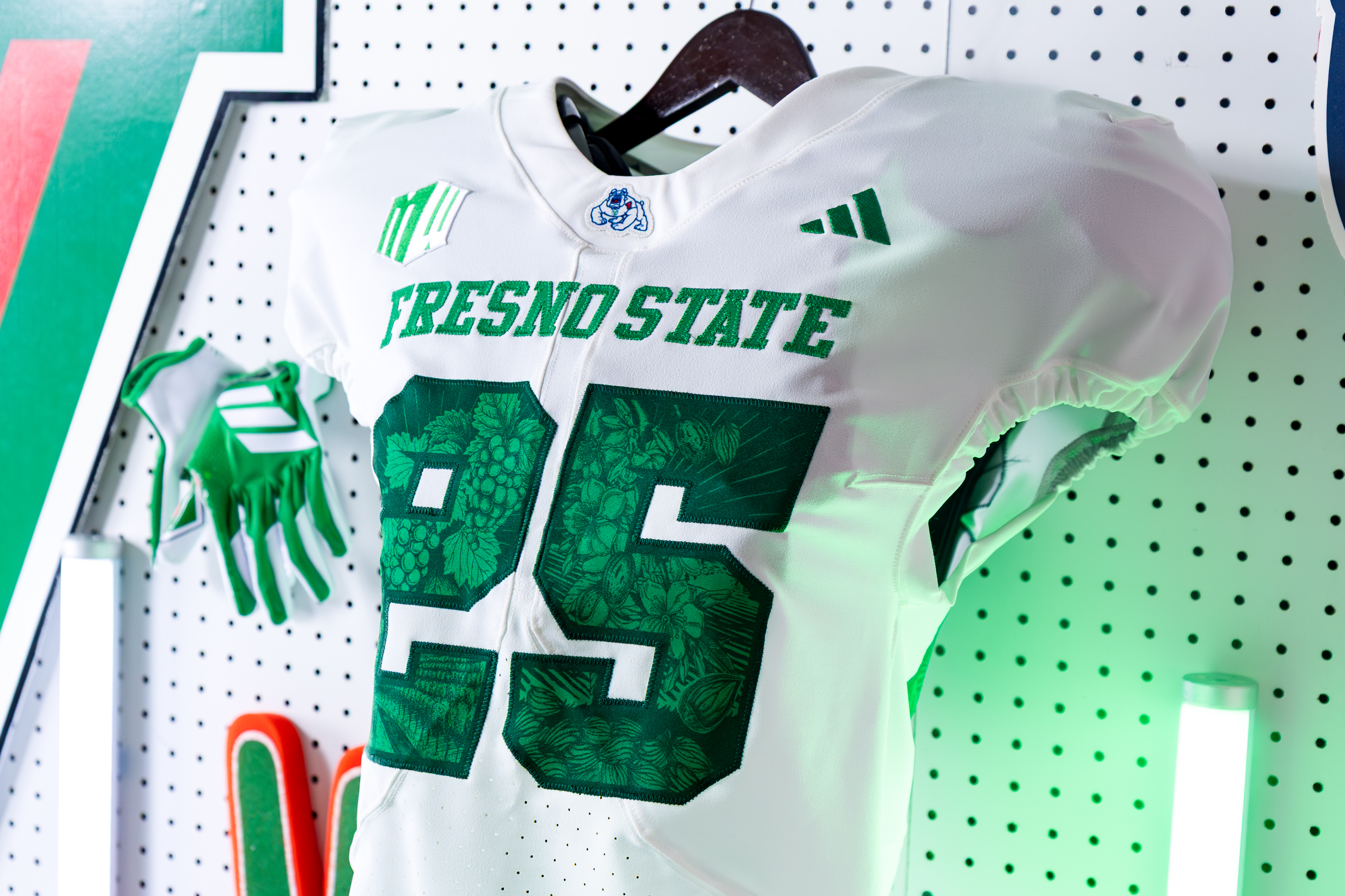 A photo of Fresno State's Ag Fest–themed football jerseys. The green numbers on the jerseys contain agriculture imagery in a dark green.