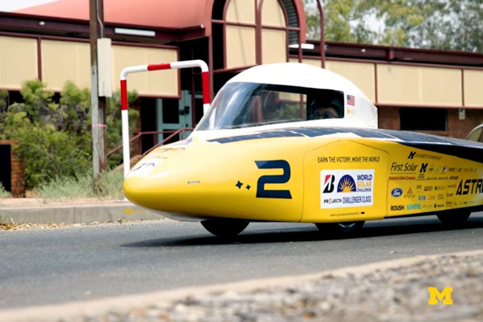 University of Michigan's yellow solar car moves down an urban street.