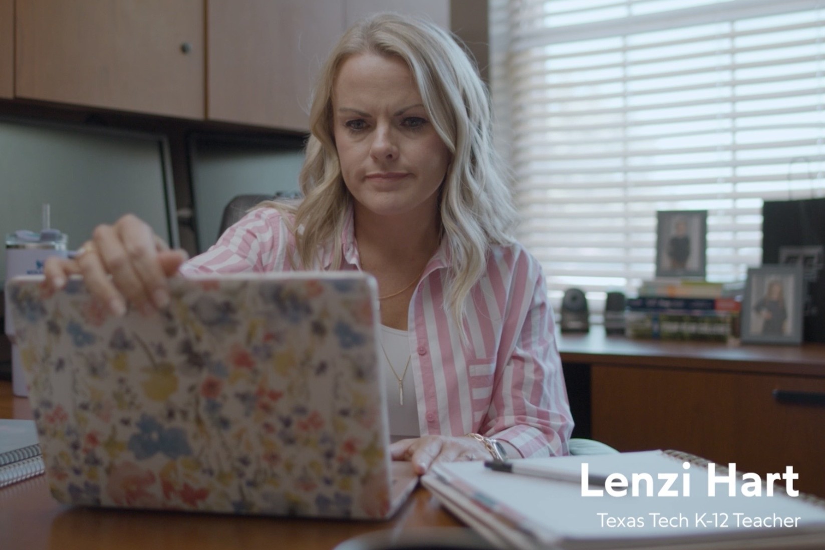 A woman sits in an office, about to close a laptop with a flora cover. The caption reads, "Lenzi Hart, Texas Tech K-12 Teacher."