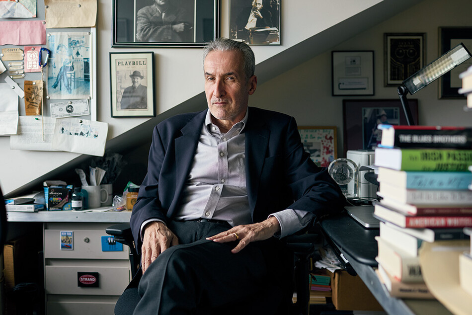 Photograph of Samuel Freedman sitting in a chair in his office. On the wall behind him hangs memorabilia.