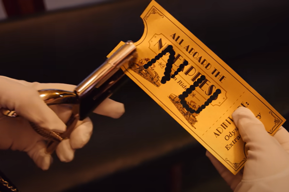 A close-up of two white gloved hands. One holds a hole punch. The other holds a gold ticket for the NU Express with the letters "N" and "U" hole-punched in its center.