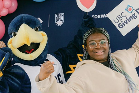 UBC's mascot poses with a person holding a sign that reads "UBC Giving Day."