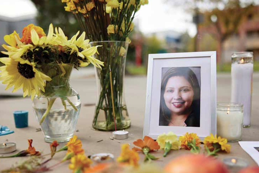 A portrait of Patricia Navarro Velez sits on the ground amongst flowers and candles.