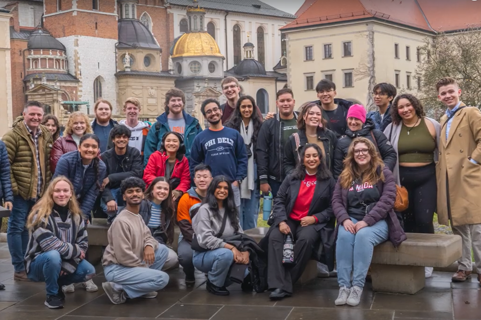 A group photo of the UTD Chamber Singers in front of buildings on their trip to Poland and Germany.