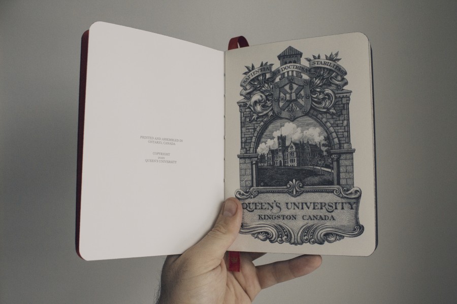 Queen's University's The Notebook open to the inside cover which shows an inked image of the university's campus