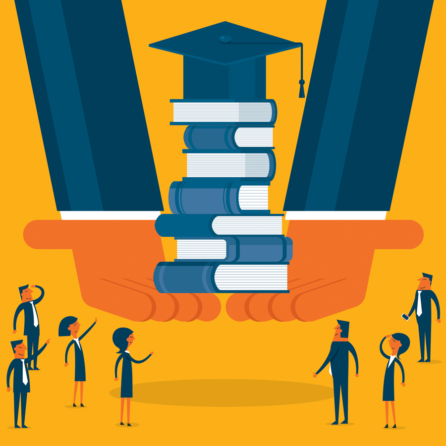 Students standing around a stack of books with a graduation cap on top.