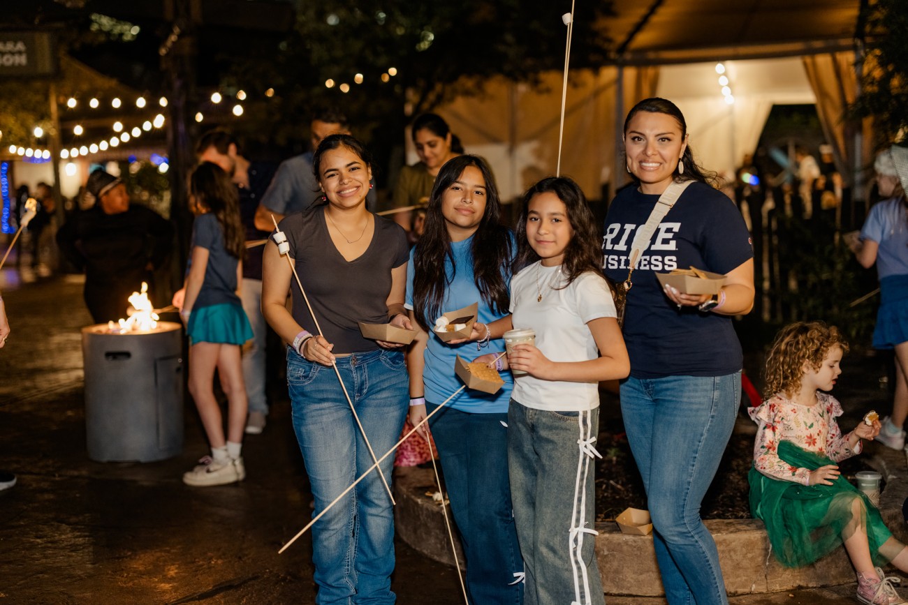 Family smiles while holding marshmallows to make smores with