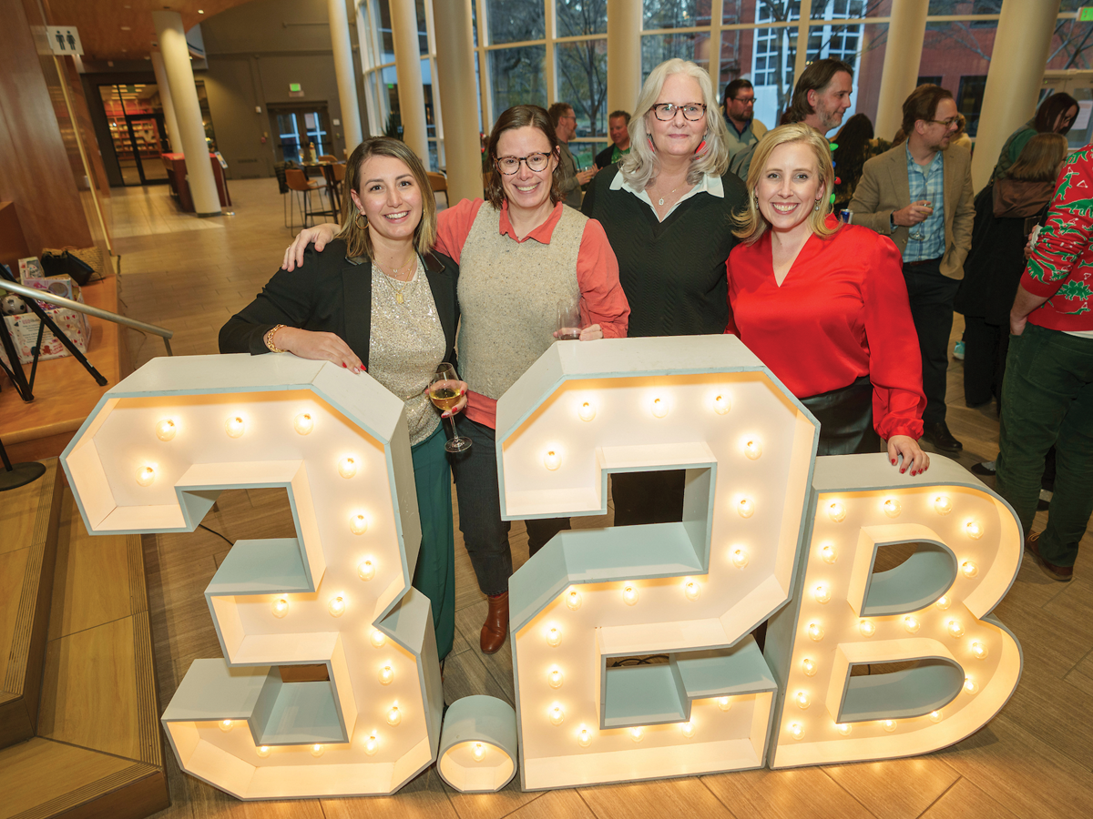 Vanderbilt alumni and staff pose in front of large 3.2B light display