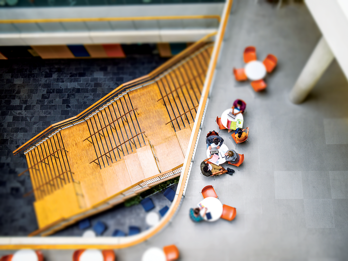 Focus blur shot of people sitting around tables in an indoor terraced atrium