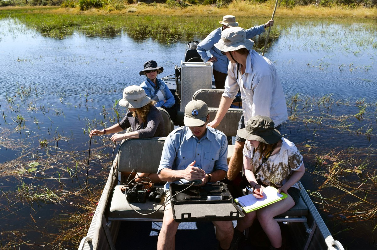 students taking water samples on a boat in a lake