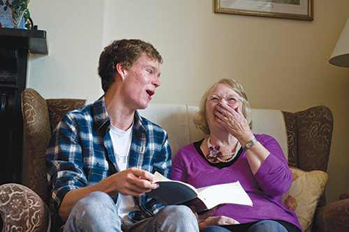Young man and old woman on sofa discussing book