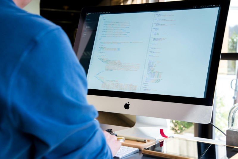A screen displaying lines of code, and a person typing.