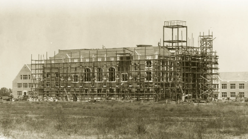 A sepia-toned archival photo of a campus building under construction.