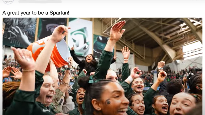 Screenshot from MSU's year in review video shows a screenshot of the Facebook post with the caption "A great year to be a Spartan!" The image is of its girls gymnastics team celebrating their championship win.