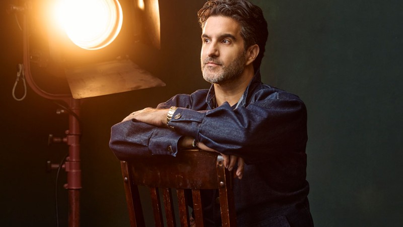 Portrait of Andy Dunn. He sits backwards on a chair, a studio light on behind him.