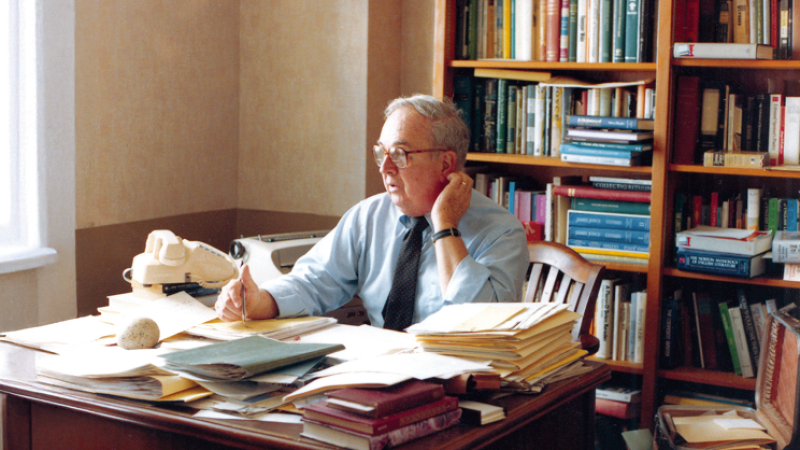 A photo of Edward F. Callahan sitting at his desk in his office.