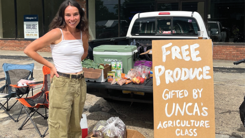 UNCA Student minding produce stand from back of pick-up truck