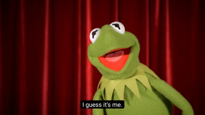 Kermit the Frog says, "I guess it's me" in front of a red curtain.