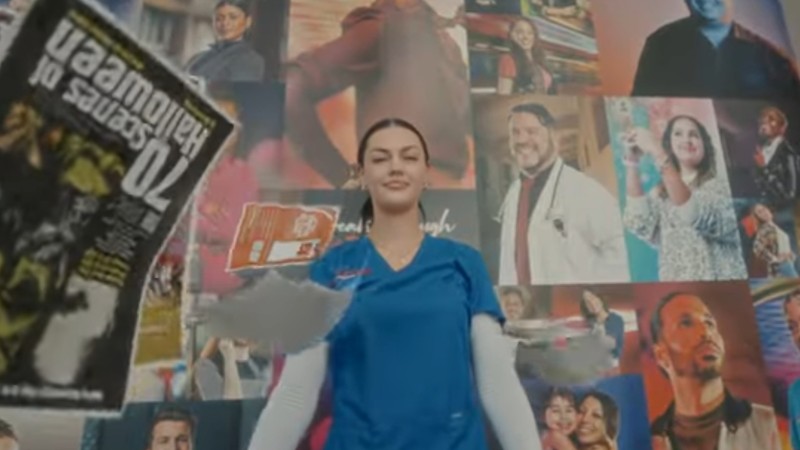 A student who works at Barry University's student-run advertising company stands in front of a wall covered in a collage of portraits. Single-page ads rain from the sky around her.