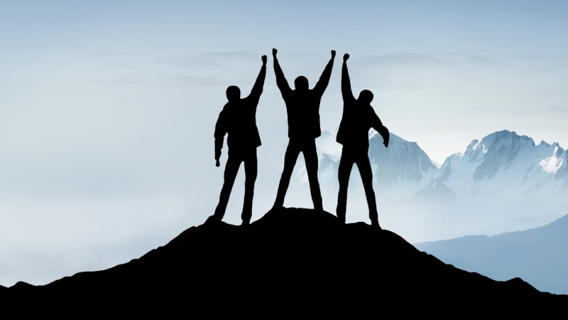 group in silhouette on mountain top