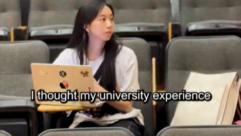 Estella, a student at TMU sits in a lecture hall, her laptop open in front of her.