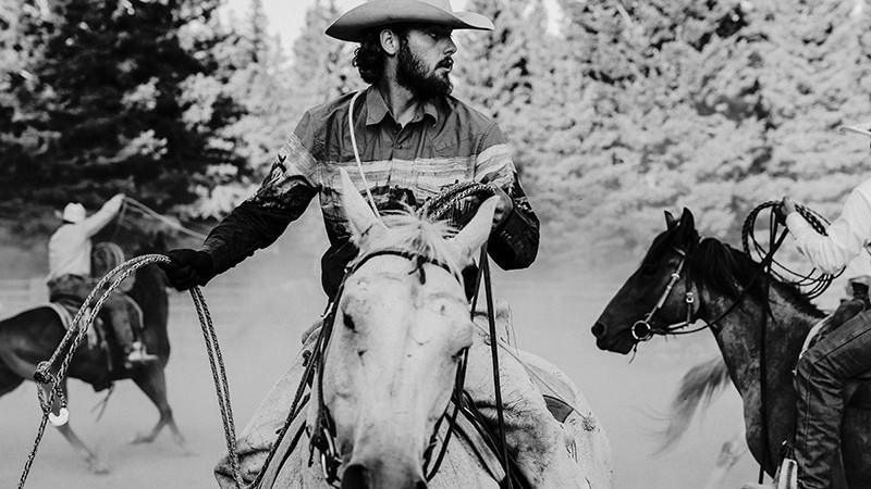 Photograph of Tristen Ellison riding a horse, rope in hand.