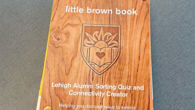 Photo of the wood-patterned cover of the Little Brown Book. It reads: "Lehigh Alumni Sorting Quiz and Connectivity Creator: Helping you discover ways to expand your South Mountain experience."
