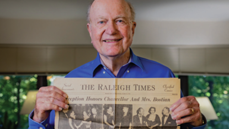A flyer features a red background, white text that reads, "Thank you for being Loyal Like Lloyd." and a picture of Lloyd Bostian holding an old issue of The Raleigh Times.