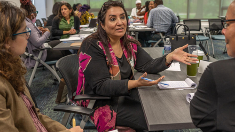 Diverse faculty discuss in small groups in a classroom.
