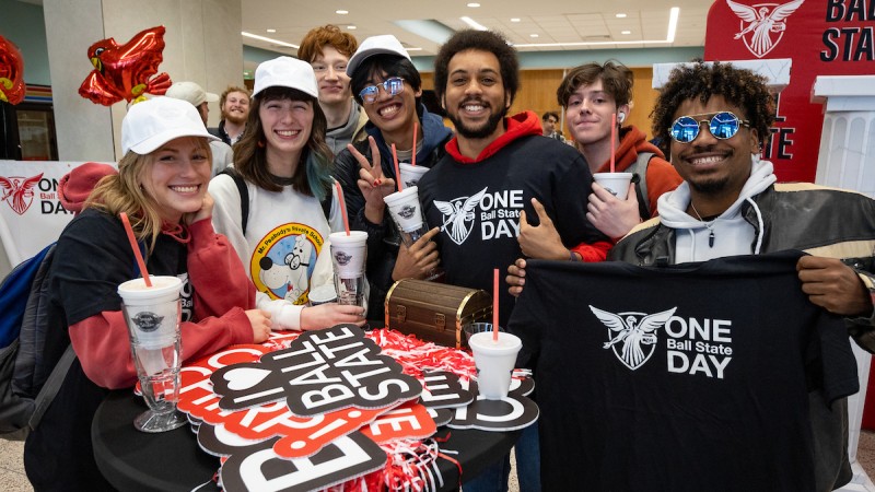 A group of Ball State students gather around a table covered in Ball Sate swag.