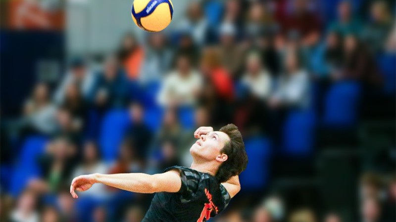 Owyn McInnis jumps in the air, preparing to hit a yellow volleyball.