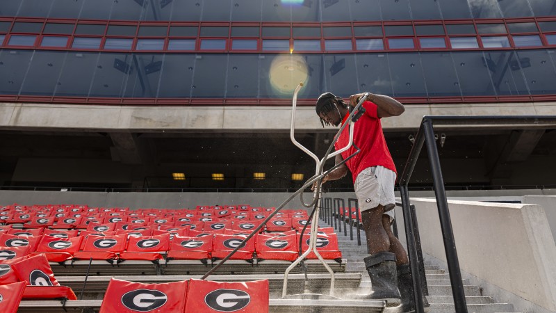 A man power washes the stands in the University of Georgia's football stadium.