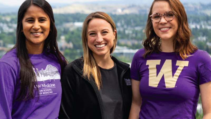Three University of Washington students pose for camera wearing purple and black UW gear. 