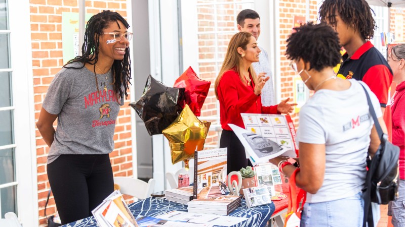 A photo from the Terp Book Fair. Two people look at flyers on one side of a table.