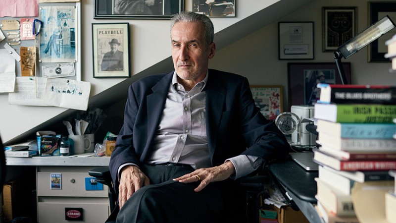 Photograph of Samuel Freedman sitting in a chair in his office. On the wall behind him hangs memorabilia.