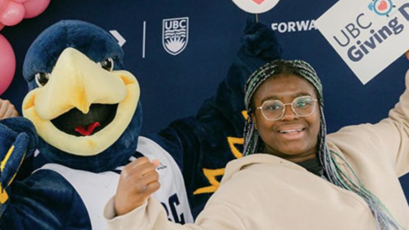 UBC's mascot poses with a person holding a sign that reads "UBC Giving Day."