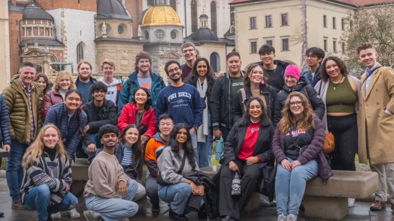 A group photo of the UTD Chamber Singers in front of buildings on their trip to Poland and Germany.