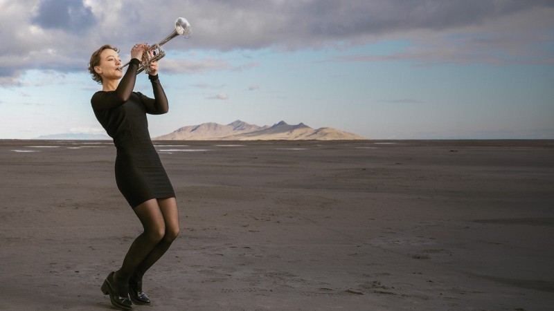 A University of Utah music student in heels and concert dress plays her trumpet on the Great Salt Lake mudflats.