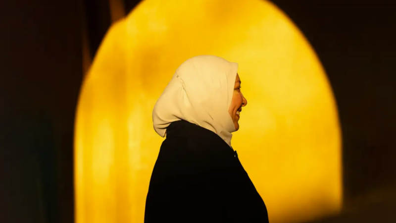 A photo of Rania Awaad. Shadows create a sunlight-illuminated arch behind her profile.