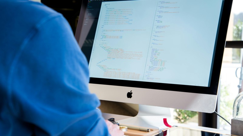 A screen displaying lines of code, and a person typing.